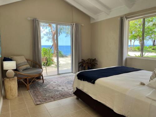 a bedroom with a bed and a chair and a window at Rockpools - 5 Bedroom Oceanfront Villa in Hideaway Island