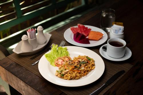 a wooden table with plates of food on it at Kemala Living Sanur in Sanur