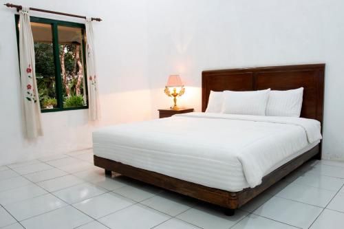 a bedroom with a large white bed with a window at Omah Kebon Guest House in Temanggung