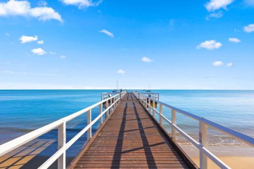 a wooden pier stretches out into the ocean at Private Poolside Villa in Urangan