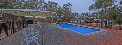 a deck with chairs and an umbrella and a swimming pool at Tiny Away Escape at Granite Belt - Sommerville Valley in Stanthorpe