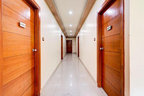 a corridor with wooden doors and white tiles at Super Townhouse MG Road Near Commercial Street in Bangalore