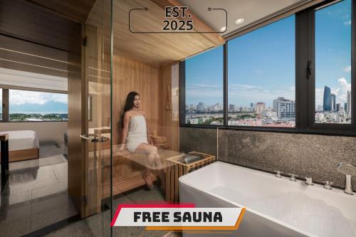 a woman is sitting in a bathroom with a tub at Rest Hotel & Apartment in Da Nang