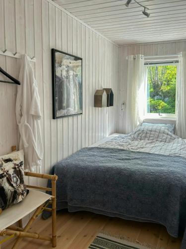 a bedroom with a bed and a window and a chair at Cabin With Views Over Straumsundet in Øygarden