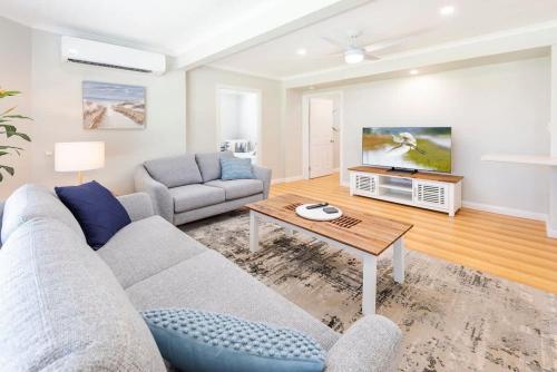 a living room with a couch and a table at Coastal Getaway - Walk to Beach in Urangan