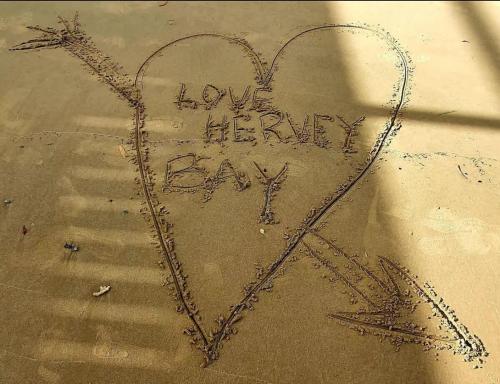 a heart drawn in the sand with the words love happy bay at Coastal Getaway - Walk to Beach in Urangan