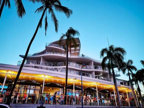 a large building with palm trees in front of it at Coastal Getaway - Walk to Beach in Urangan