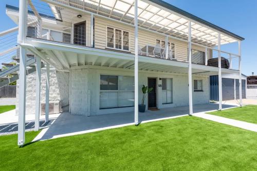 a large white house with a green yard at Coastal Escape-Walk to Beach in Urangan