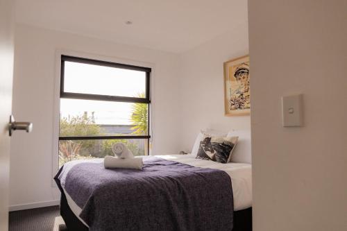 een slaapkamer met een bed en een raam bij Lifebuoy Beach House Bicheno in Bicheno