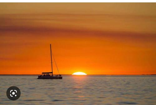 a boat in the water with the sunset in the background at Coastal Family Escape in Urangan