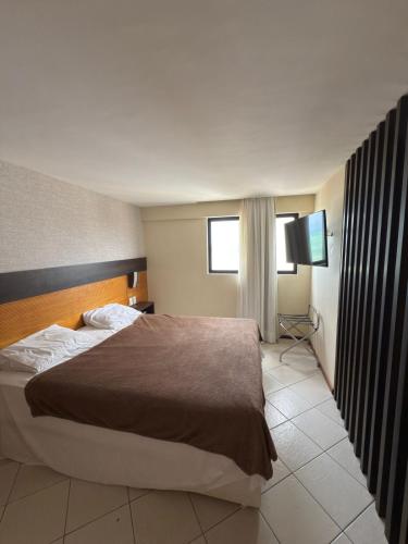 une chambre d'hôtel avec un lit et une télévision dans l'établissement Quality suites natal apto 1009, à Natal