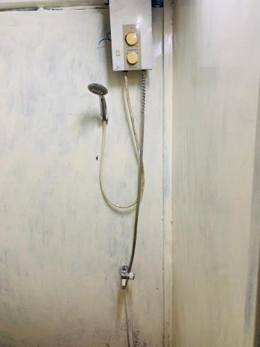 a shower with a hose attached to a wall at Chill Door Homestay in Ấp Long Ðại