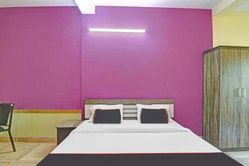 a bedroom with a bed and a purple wall at Collection O EXPRESS SUITES in Calicut