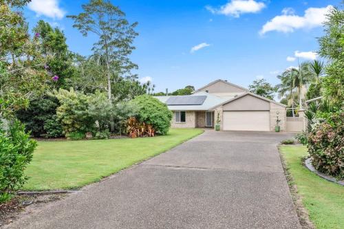 a house with a driveway in a yard at Private Family Retreat - Pool Spa Tennis firepit in Hervey Bay
