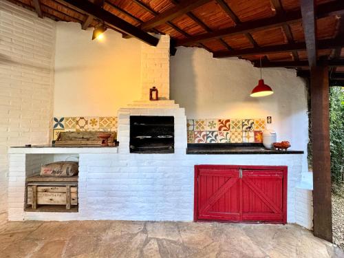 an outdoor kitchen with red doors and a brick oven at Luxury Retreat, Vale do Cafe, RJ in Paty do Alferes