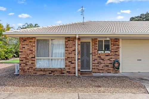 a brick house with a window and a garage at Sea King - Duplex Walk to Beach in Urangan