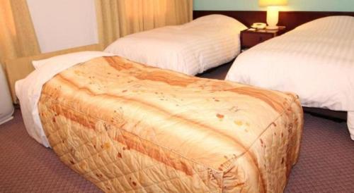 a hotel room with two beds and a ottoman at Oita Century Hotel in Oita