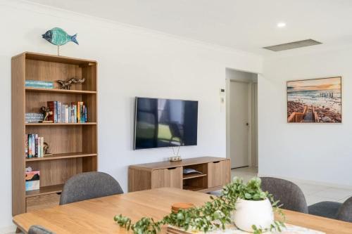 a dining room with a table and a tv at Marine Bliss-4Bd Beach Access in Urangan