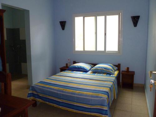 Cama en habitación azul con ventana en Residence Kathyly, en Antsiranana