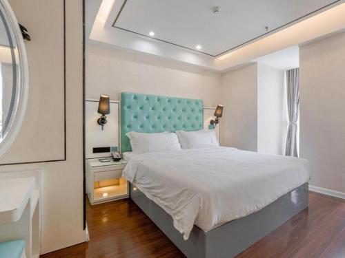 a bedroom with a large bed with a blue headboard at Xana Lite Anqing Yuexi Swan Squre Branch in Yuexi