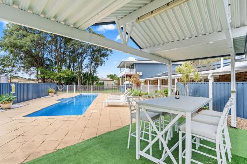 a patio with a white table and chairs and a pool at Whitesands Family Beachhouse in Urangan