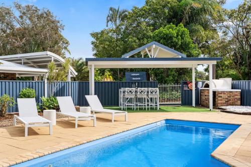 a pool with chairs and a gazebo with a table and a grill at Whitesands Family Beachhouse in Urangan