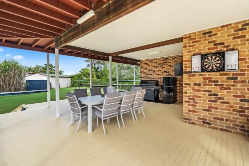 a patio with a table and chairs and a brick wall at Whitesands Family Beachhouse in Urangan
