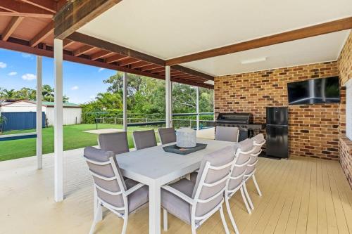 a dining room with a white table and chairs at Whitesands Family Beachhouse in Urangan