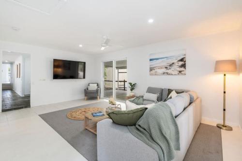 a white living room with a couch and a table at Whitesands Family Beachhouse in Urangan