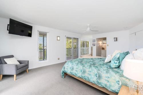 a bedroom with a bed and a tv and a chair at Whitesands Family Beachhouse in Urangan