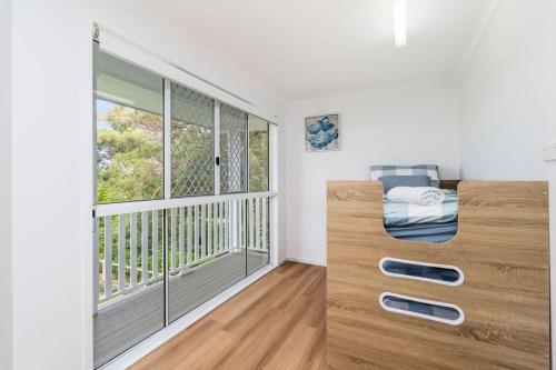 a bedroom with a bed and a large window at Whitesands Family Beachhouse in Urangan