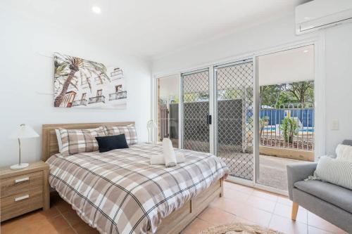 a bedroom with a bed and a couch and a window at Whitesands Family Beachhouse in Urangan