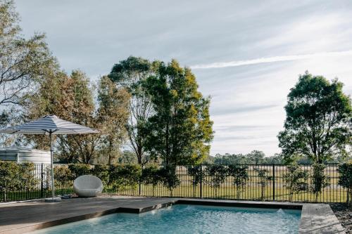 a swimming pool with a fence and an umbrella at Emma's Cottage Vineyard in Lovedale