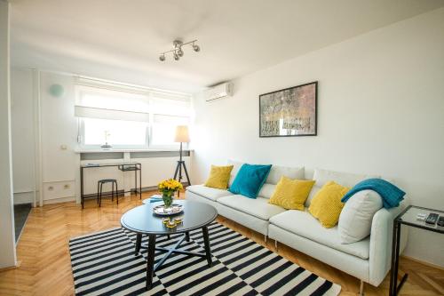 a living room with a white couch and a table at Hendrix Bridge Apartment in Zagreb