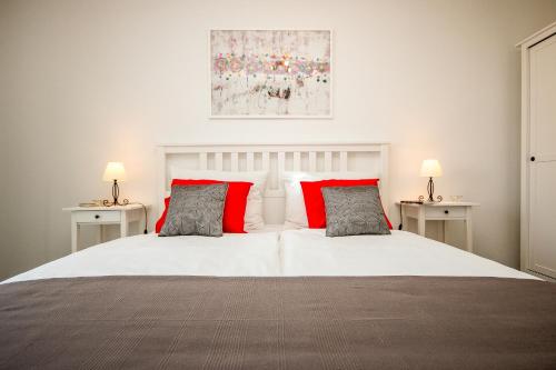 a bedroom with a white bed with red pillows at Hendrix Bridge Apartment in Zagreb