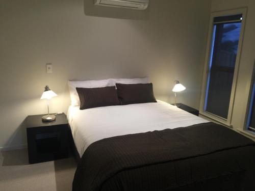 ein Schlafzimmer mit einem großen weißen Bett mit zwei Lampen in der Unterkunft Villas on the Bay Kingscote in Kingscote