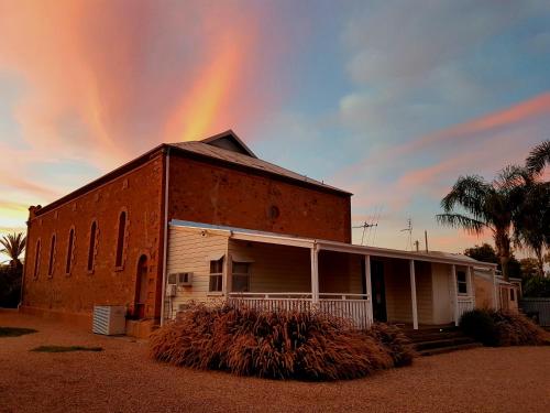 a rainbow in the sky over a brick building at Broken Hill Outback Church Stay in Broken Hill