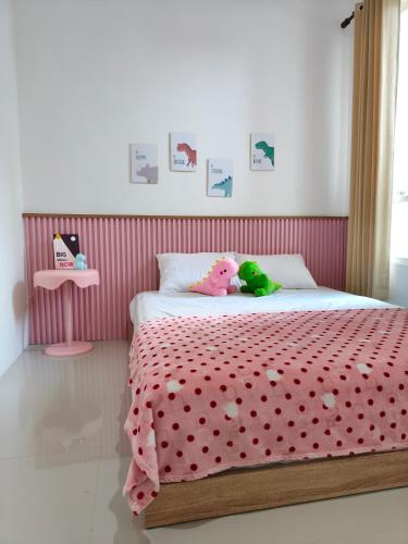 ein Schlafzimmer mit einem Bett mit einer rosa gepunkteten Tagesdecke in der Unterkunft Villa Dino Park Batu in Karangploso