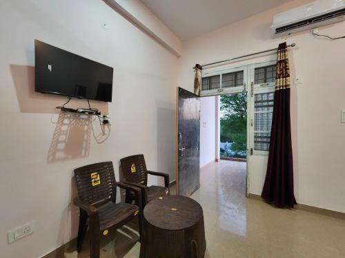a living room with two chairs and a table and a tv at Thakur Guest House in Jawāla Mukhi Road