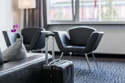 uma mala sentada no chão num quarto com cadeiras em ProfilHotels Mercur em Copenhague