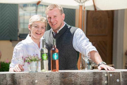a man and a woman standing at a counter with wine bottles at Gasthof zum Weißen Lamm in Sommerach