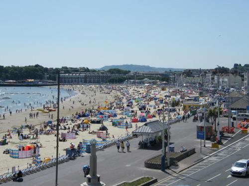 a beach filled with lots of parked cars and umbrellas at Weymouth Beach B&B - Adult Only in Weymouth