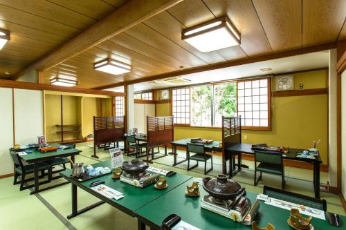 a large room with tables and chairs and windows at Oyado Hisaya in Kami