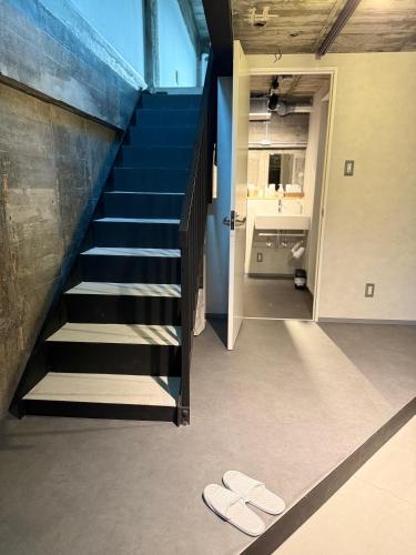 a staircase in a house with slippers on the floor at RePORTHOTEL in Yaizu