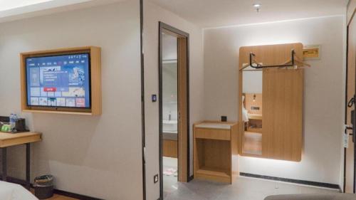 a room with a bathroom with a tv on a wall at GreenTree Inn Express Datong High-Speed Railway Station Old City Wall in Datong