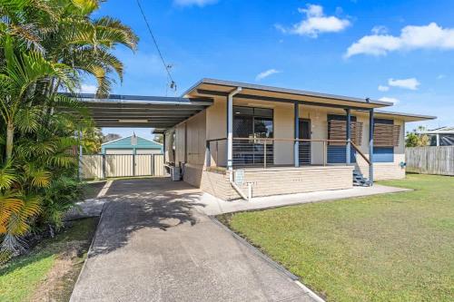 a house with a garage and a palm tree at Coastal Cottage in Urangan