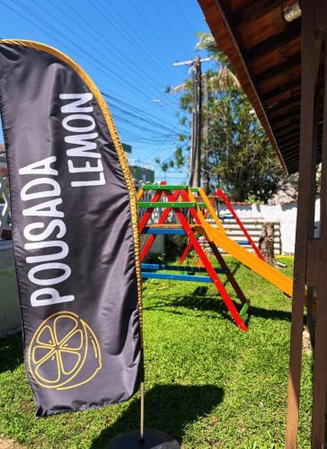 a sign in a park with a playground at Pousada Lemon Suítes - Praia do Sesc Acesso Vista Linda e Centro in Bertioga