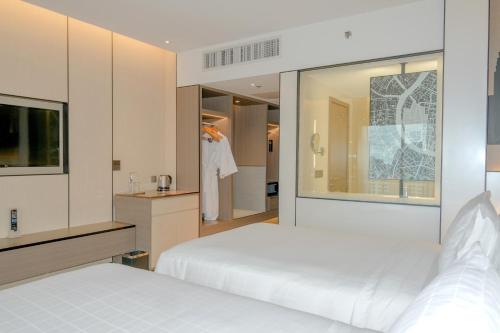 a bedroom with two beds and a mirror at Pathumwan Princess Hotel - SHA Extra Plus Certified in Bangkok