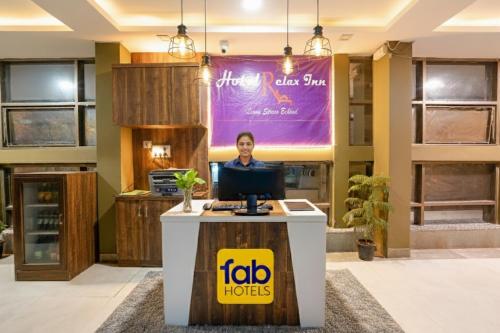 a man sitting at a desk in a lobby with a computer at FabHotel Relax - opp Hotel Leela in Gandhinagar