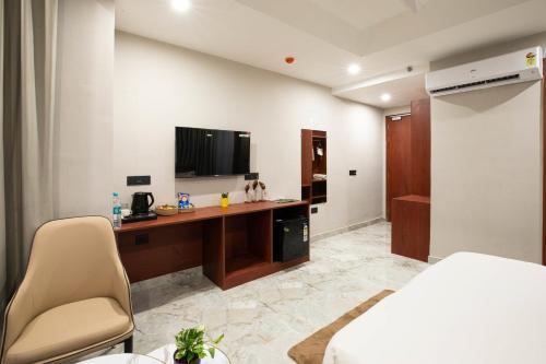 a bedroom with a bed and a desk with a television at Aarchh Regency Noida in Noida